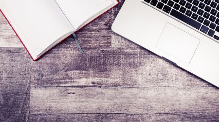 Laptop and a notebook for writing from above view on a wooden background